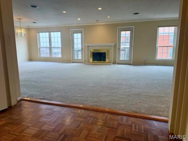 10367 Oxford Hill Dr Unit 26, Saint Louis, MO 63146 - unfurnished living room with ornamental molding, carpet, a chandelier, a brick fireplace, and recessed lighting