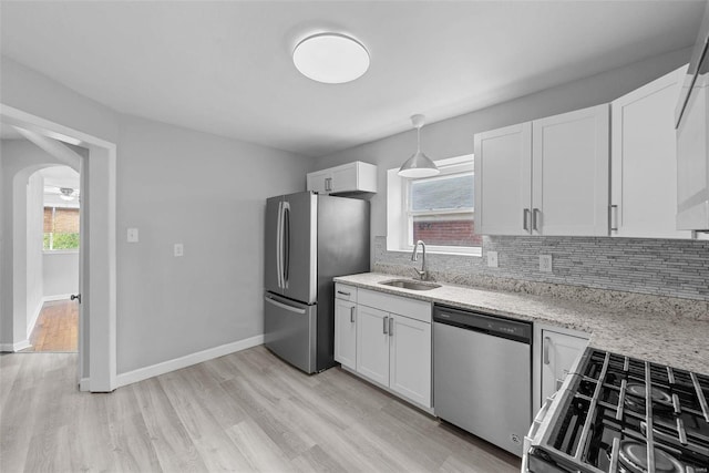 kitchen with appliances with stainless steel finishes, a sink, backsplash, and white cabinetry