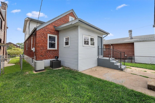 back of house with central AC unit and brick siding
