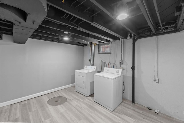 laundry room with washing machine and clothes dryer and light wood-type flooring