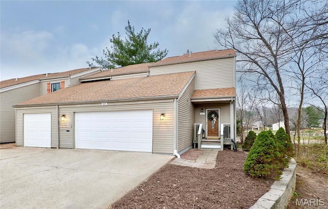 multi unit property with an attached garage, concrete driveway, and roof with shingles