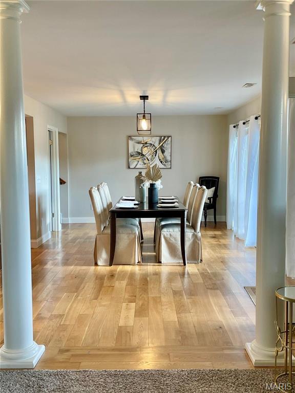 dining area with decorative columns, baseboards, and light wood-style flooring