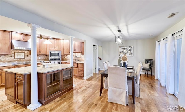 dining area with decorative columns, light wood-type flooring, and baseboards
