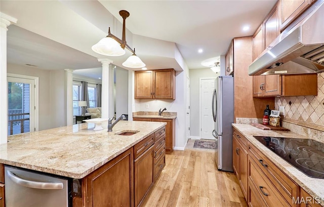 kitchen featuring under cabinet range hood, stainless steel appliances, a sink, decorative columns, and recessed lighting