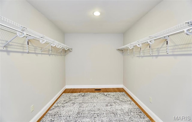 walk in closet with wood finished floors