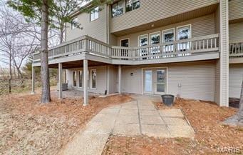rear view of house featuring a wooden deck and a patio