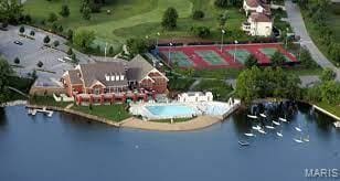 aerial view of property and surrounding area with a nearby body of water and a pool area