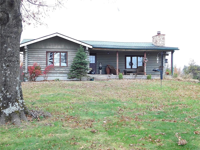 view of front of home featuring a chimney, a porch, a front yard, and log exterior
