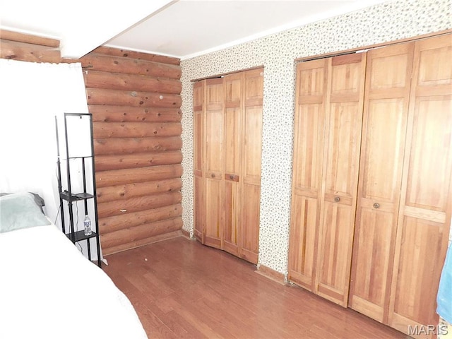 5 Sherwood Meadows Cir, Marthasville, MO 63357 - bedroom featuring log walls, light wood-style flooring, wallpapered walls, and multiple closets