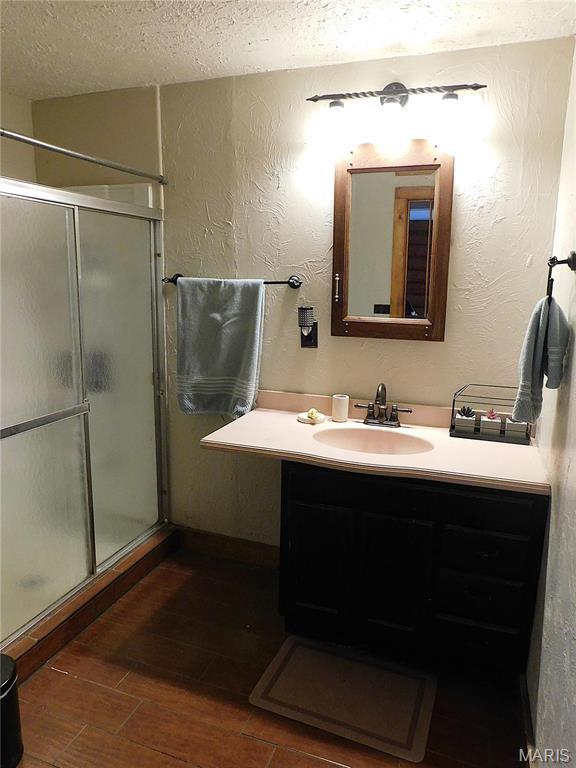 5 Sherwood Meadows Cir, Marthasville, MO 63357 - bathroom featuring a textured ceiling, vanity, a shower stall, wood finished floors, and a textured wall
