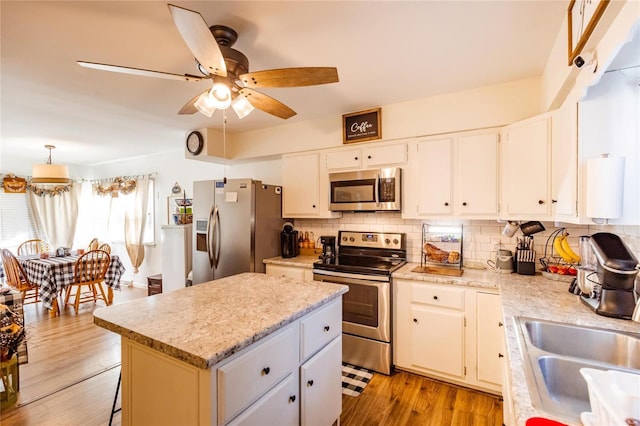 1040 N Kingshighway, Sikeston, MO 63801 - kitchen with appliances with stainless steel finishes, a ceiling fan, a sink, a kitchen island, and backsplash