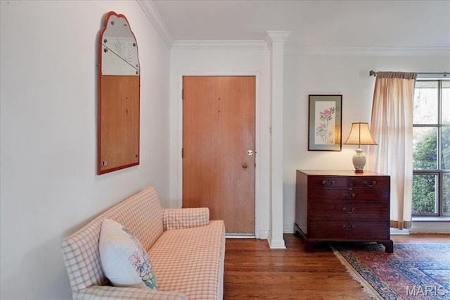 living area with wood finished floors, ornamental molding, and baseboards