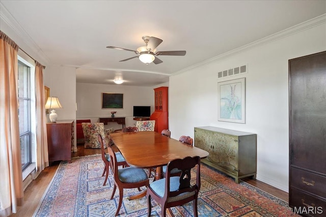 dining area with wood finished floors, ceiling fan, and crown molding