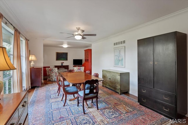 dining space with wood finished floors, ceiling fan, and ornamental molding