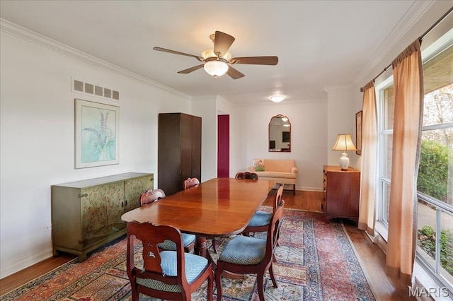 dining room with dark wood-type flooring, crown molding, baseboards, and a ceiling fan