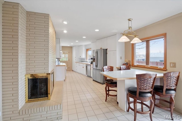 kitchen with appliances with stainless steel finishes, plenty of natural light, light countertops, a kitchen bar, and recessed lighting