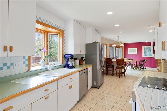 kitchen featuring appliances with stainless steel finishes, a sink, white cabinets, light tile patterned floors, and recessed lighting