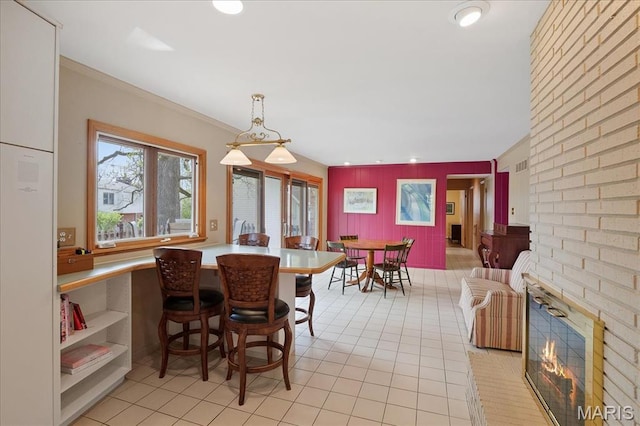 dining area with light tile patterned floors, ornamental molding, recessed lighting, and a brick fireplace