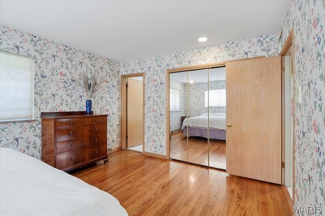 bedroom featuring wallpapered walls, wood finished floors, and a closet