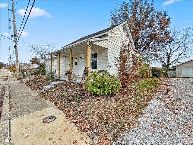 view of front of property featuring a porch, a detached garage, and driveway