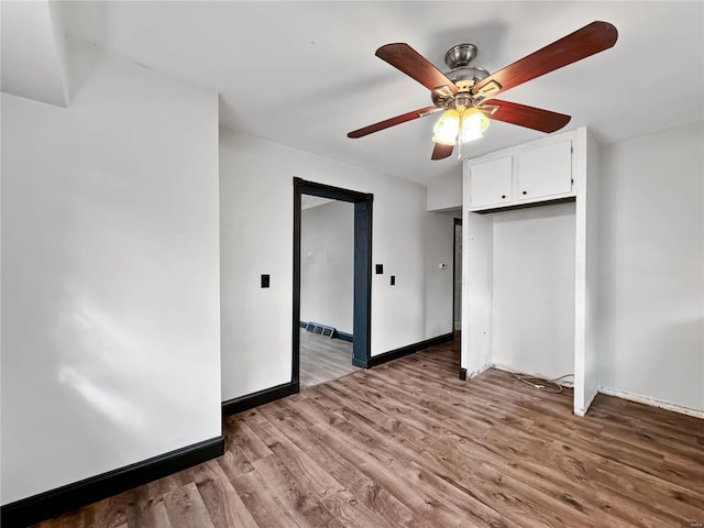 unfurnished bedroom with wood finished floors, baseboards, a ceiling fan, and a closet
