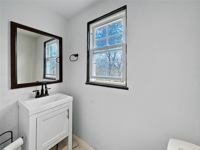 half bathroom with vanity, toilet, and baseboards
