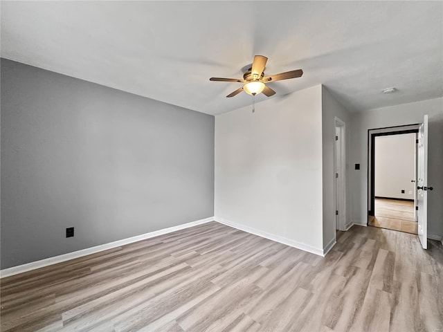 empty room with ceiling fan, wood finished floors, and baseboards