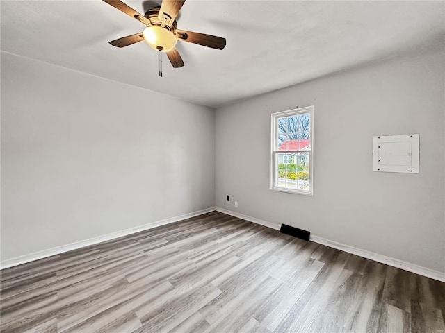 unfurnished room featuring wood finished floors, ceiling fan, baseboards, and electric panel
