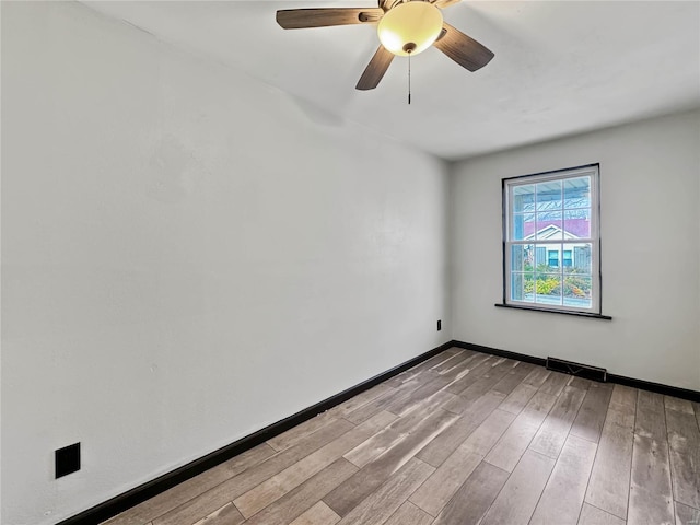 empty room with wood finished floors, baseboards, and a ceiling fan