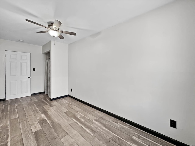 unfurnished room featuring ceiling fan, light wood-type flooring, and baseboards