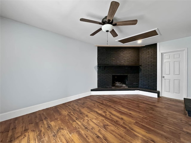 unfurnished living room with ceiling fan, wood finished floors, baseboards, and a brick fireplace