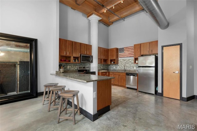 1113 Washington Ave Unit 215, Saint Louis, MO 63101 - kitchen with stainless steel appliances, a towering ceiling, brown cabinets, and concrete flooring