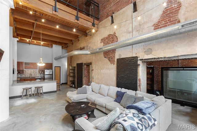 1113 Washington Ave Unit 215, Saint Louis, MO 63101 - living area with a high ceiling, concrete flooring, brick wall, and beam ceiling