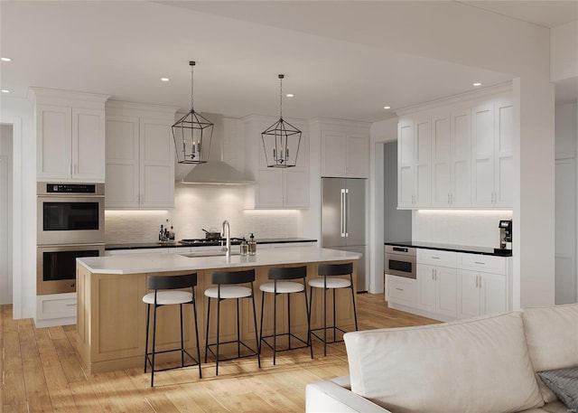 1136 Weidman Rd, Town And Country, MO 63017 - kitchen with stainless steel appliances, wall chimney exhaust hood, tasteful backsplash, light wood-style floors, and a breakfast bar