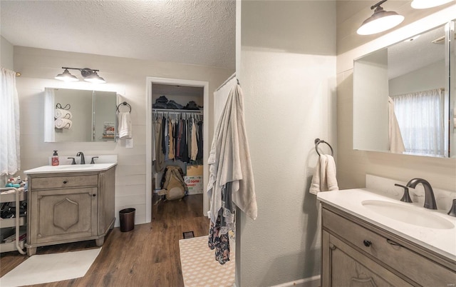 704 Ogle Dr, Richland, MO 65556 - full bathroom with wood finished floors, two vanities, a spacious closet, and a textured ceiling