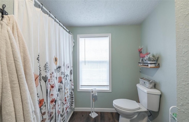 704 Ogle Dr, Richland, MO 65556 - bathroom featuring a textured ceiling, toilet, wood finished floors, baseboards, and a shower with curtain