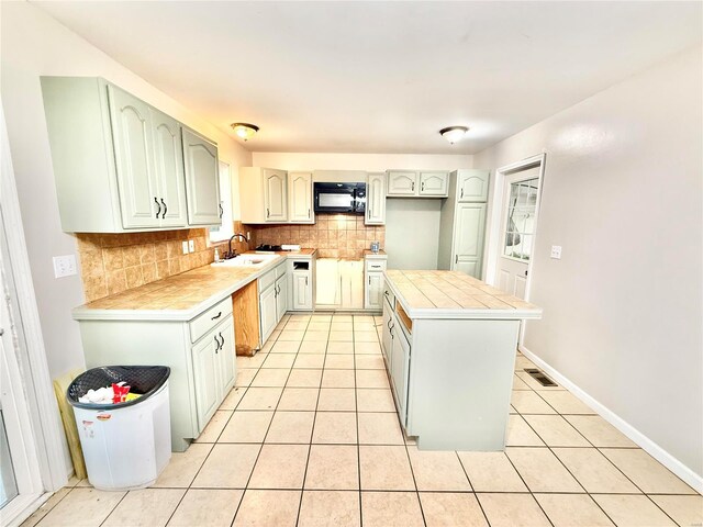2560 Birch St, Doe Run, MO 63637 - kitchen with black microwave, backsplash, light tile patterned floors, a kitchen island, and tile counters