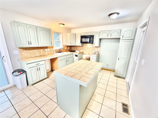 2560 Birch St, Doe Run, MO 63637 - kitchen with black microwave, a kitchen island, decorative backsplash, light tile patterned floors, and tile countertops