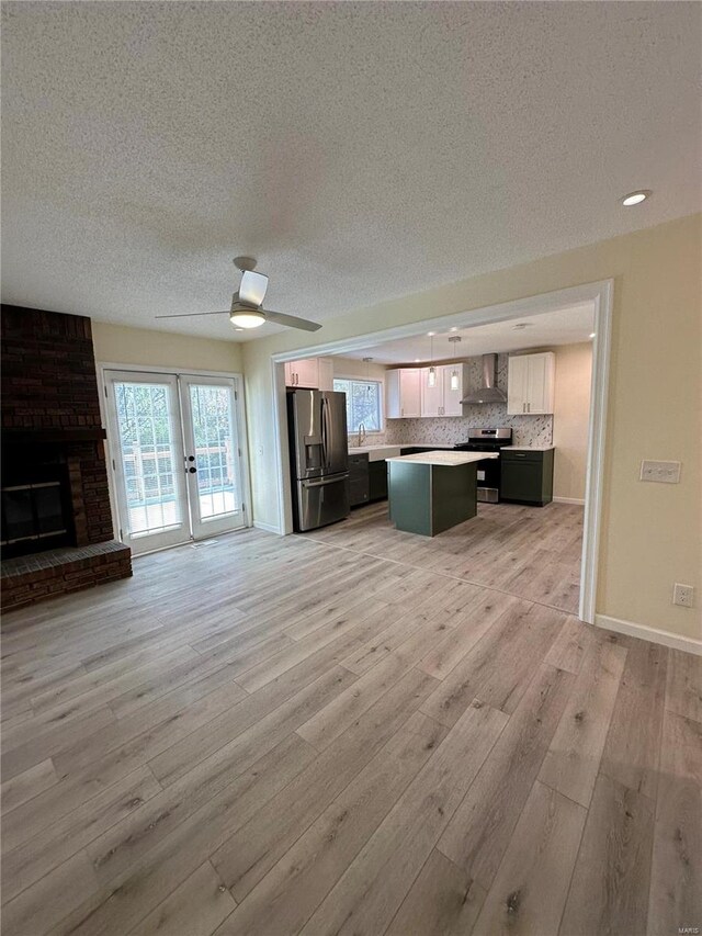 926 Justice Ct, Florissant, MO 63034 - unfurnished living room featuring a textured ceiling, light wood-style flooring, a fireplace, baseboards, and a ceiling fan