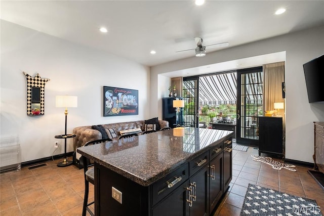 kitchen featuring a kitchen bar, recessed lighting, dark cabinets, a ceiling fan, and baseboards