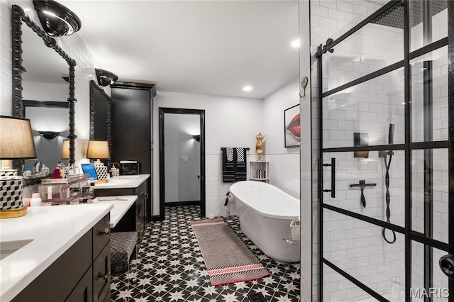 full bathroom with tile patterned floors, a freestanding tub, vanity, a stall shower, and tile walls