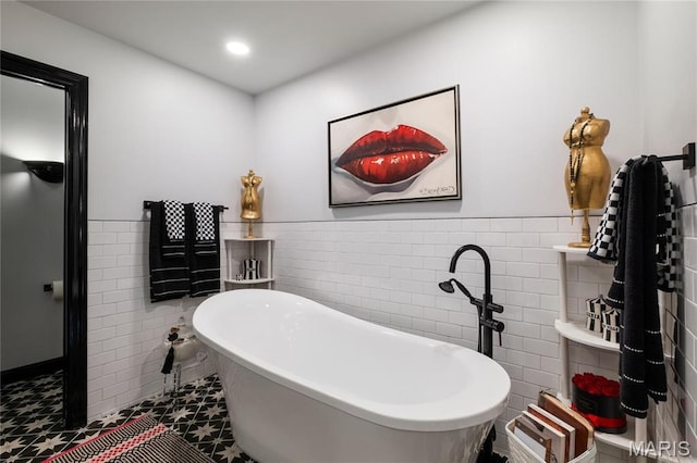 bathroom with tile walls, wainscoting, a soaking tub, and recessed lighting
