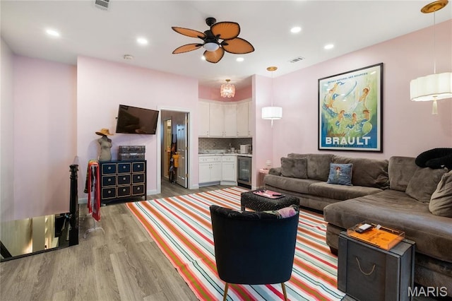 living room featuring beverage cooler, light wood-style floors, a ceiling fan, and recessed lighting