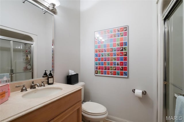 bathroom featuring toilet, a shower with door, and vanity