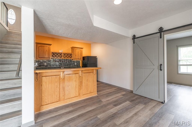 14280 County Road 8100, Rolla, MO 65401 - kitchen featuring freestanding refrigerator, wood finished floors, a peninsula, a barn door, and a textured ceiling