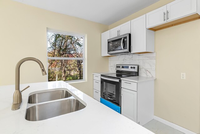 4327 Nelson Dr, Saint Louis, MO 63121 - kitchen featuring appliances with stainless steel finishes, a sink, light countertops, and white cabinetry
