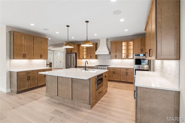 19 Beaver Dr, Creve Coeur, MO 63141 - kitchen featuring appliances with stainless steel finishes, premium range hood, a sink, light wood-type flooring, and brown cabinets