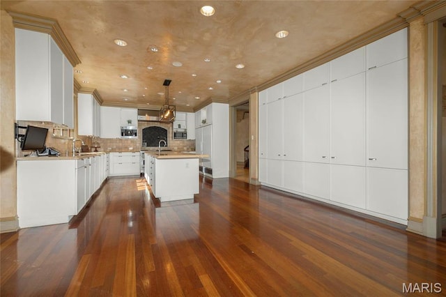 1290 Dry Ridge Rd, Town And Country, MO 63131 - kitchen featuring crown molding, stainless steel microwave, dark wood-style floors, a kitchen island with sink, and tasteful backsplash