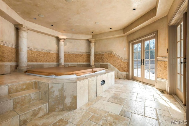 1290 Dry Ridge Rd, Town And Country, MO 63131 - bathroom with stone tile floors, french doors, decorative columns, a garden tub, and a wainscoted wall