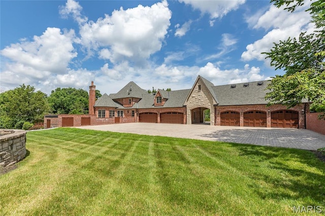 1290 Dry Ridge Rd, Town And Country, MO 63131 - rear view of house with stone siding, a lawn, an attached garage, a chimney, and driveway